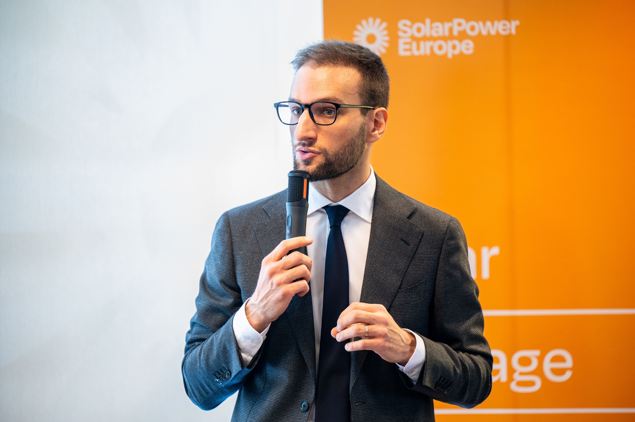 SolarPower Europe representative speaking at a professional workshop with slides in the background.