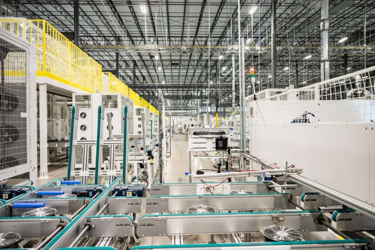 A modern solar panel manufacturing facility with rows of automated production machinery.