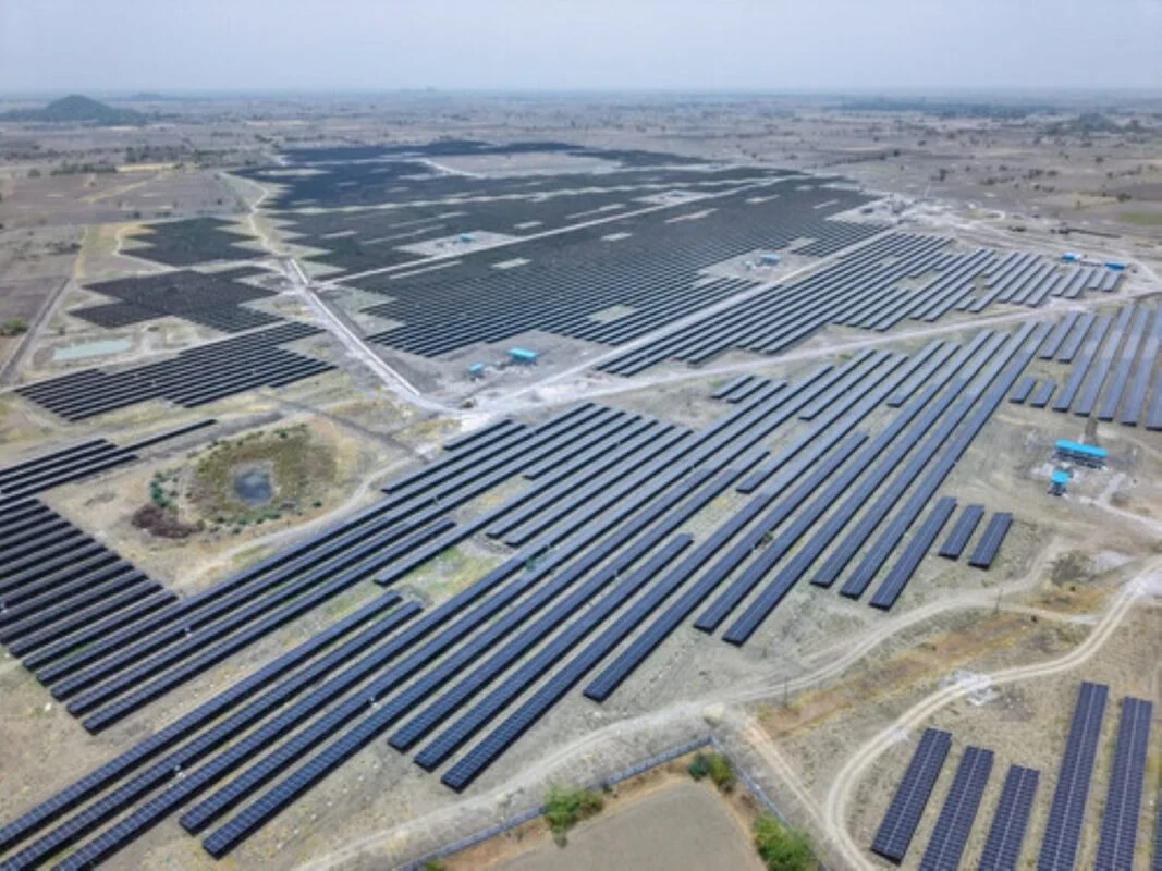Large scale solar farm utility project with bifacial modules and string inverters under a clear sky.