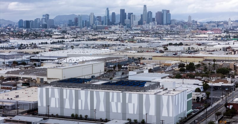 A modern data center facility with rooftop solar panels and battery storage containers nearby.