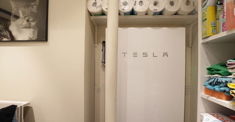 A row of Tesla Powerwall batteries installed on an exterior wall representing virtual power plant integration.