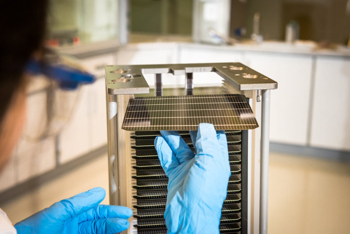 A close-up of a perovskite solar cell prototype being tested in a laboratory setting.