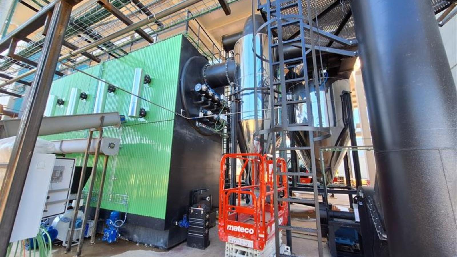 A modern industrial district heating plant integrated with a large-scale solar PV array on the roof.