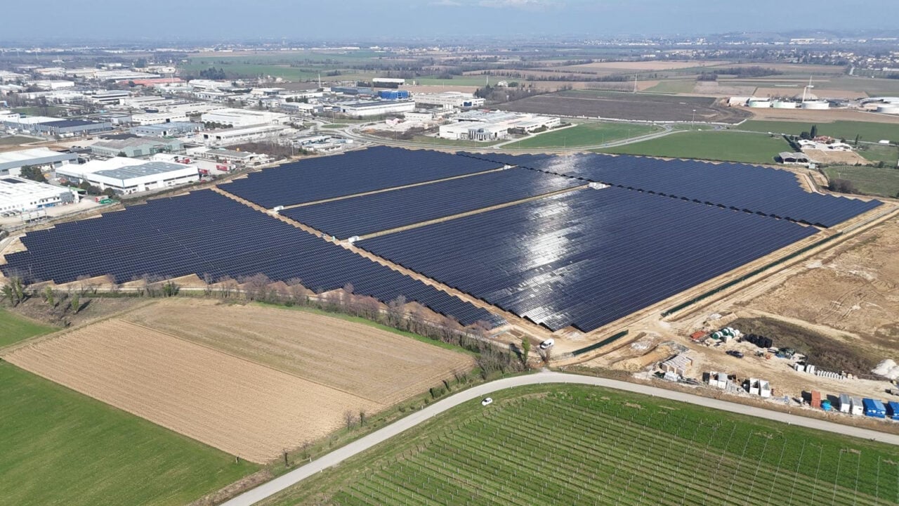 Aerial view of a large-scale solar farm installation in the Italian countryside at sunset