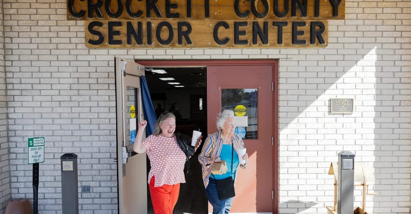 A community senior center featuring solar panels on the roof and a local neighborhood gathering.