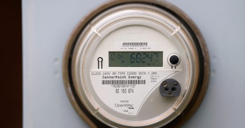 A technician inspecting a smart meter installation with a digital tablet displaying real-time energy analytics.