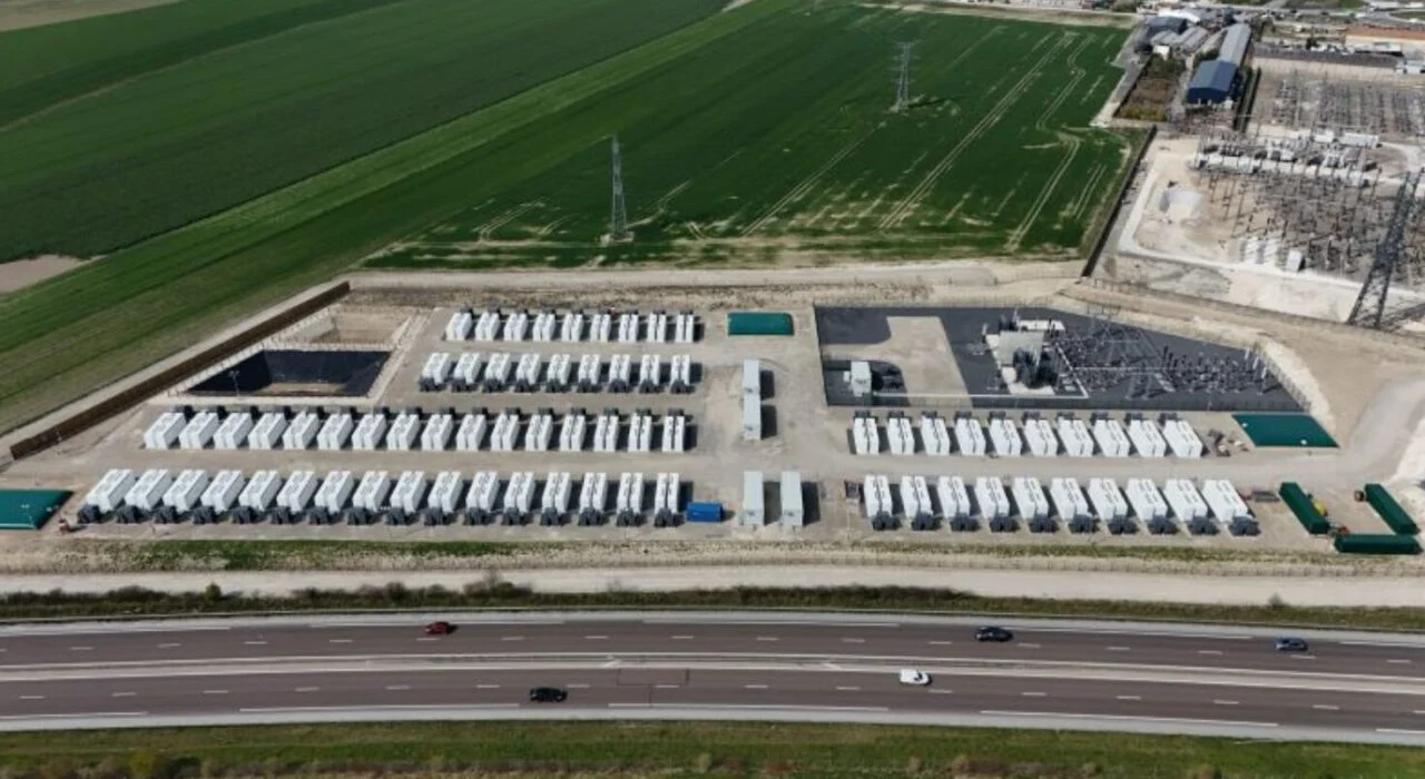 Rows of white utility-scale battery containers at a large-scale BESS commissioning site in Europe.