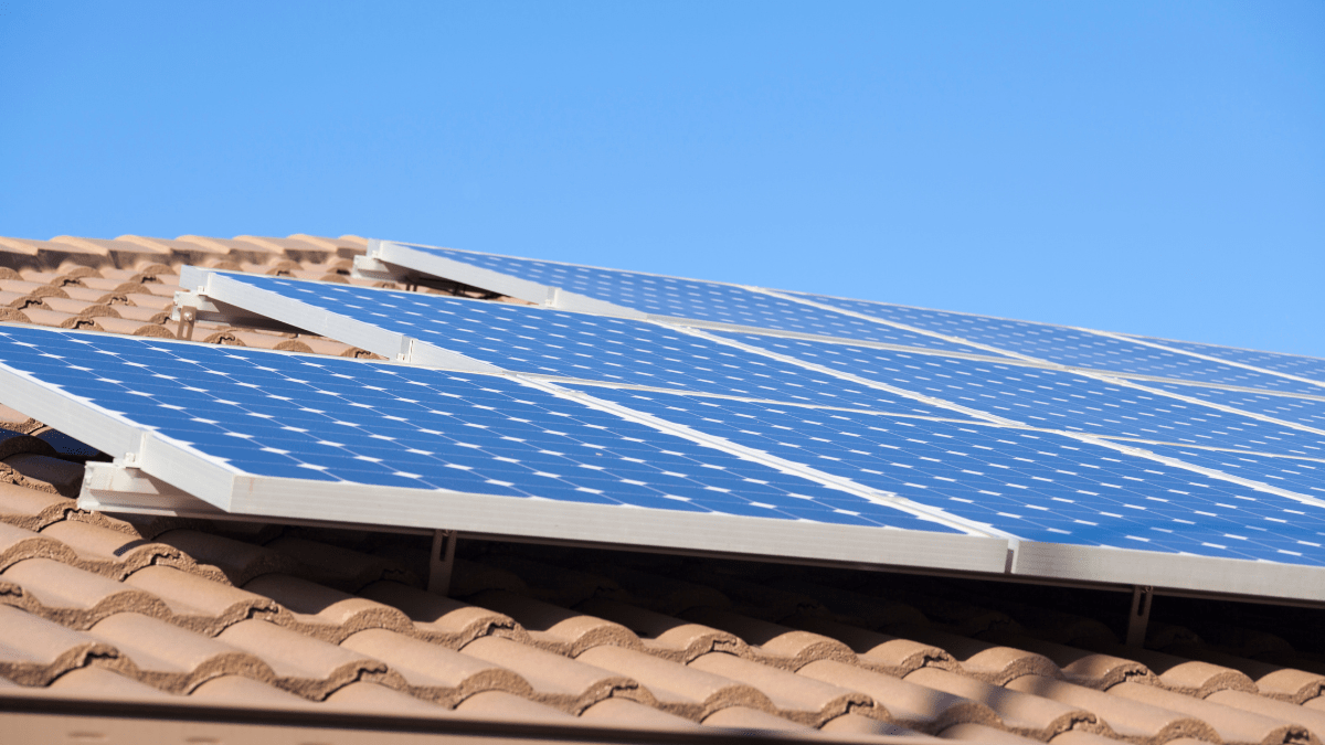 Modern solar panels installed on a residential rooftop with a cloudy sky backdrop