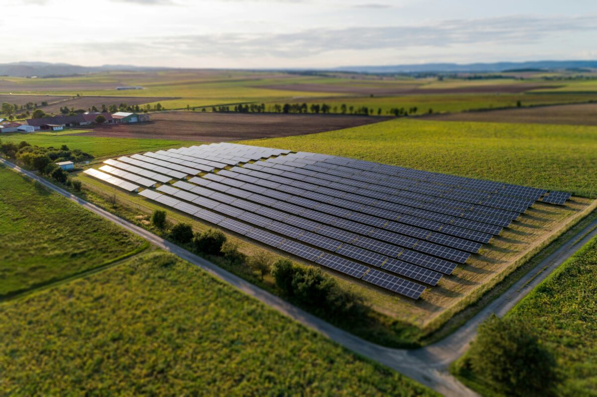 Large scale utility solar array spanning across flat Midwestern plains under a clear sky.
