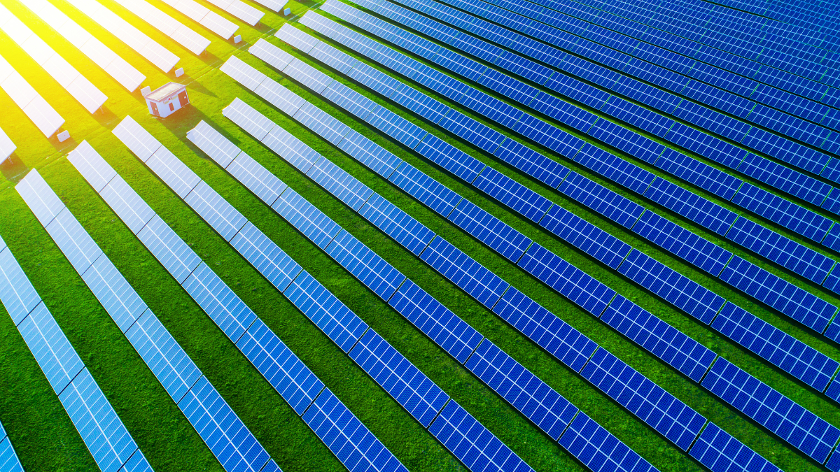 Aerial view of a large-scale solar farm installation under a bright blue sky.
