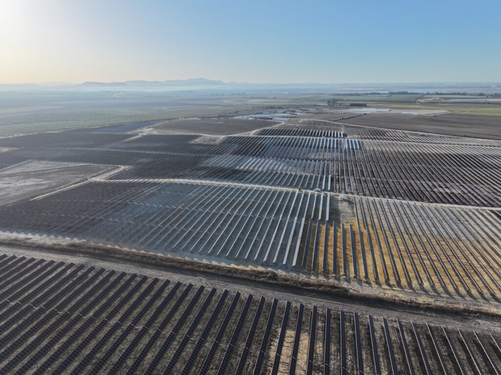 Aerial view of a large-scale solar farm in the Spanish countryside with transmission lines.