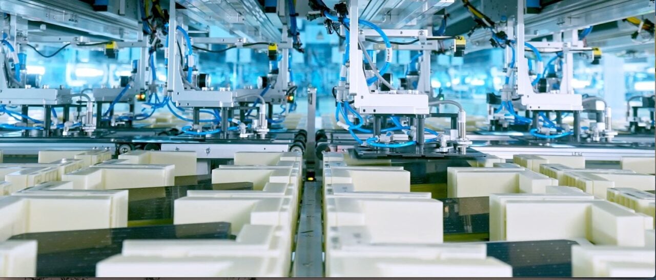 A modern solar panel manufacturing facility with rows of photovoltaic cells on an assembly line.