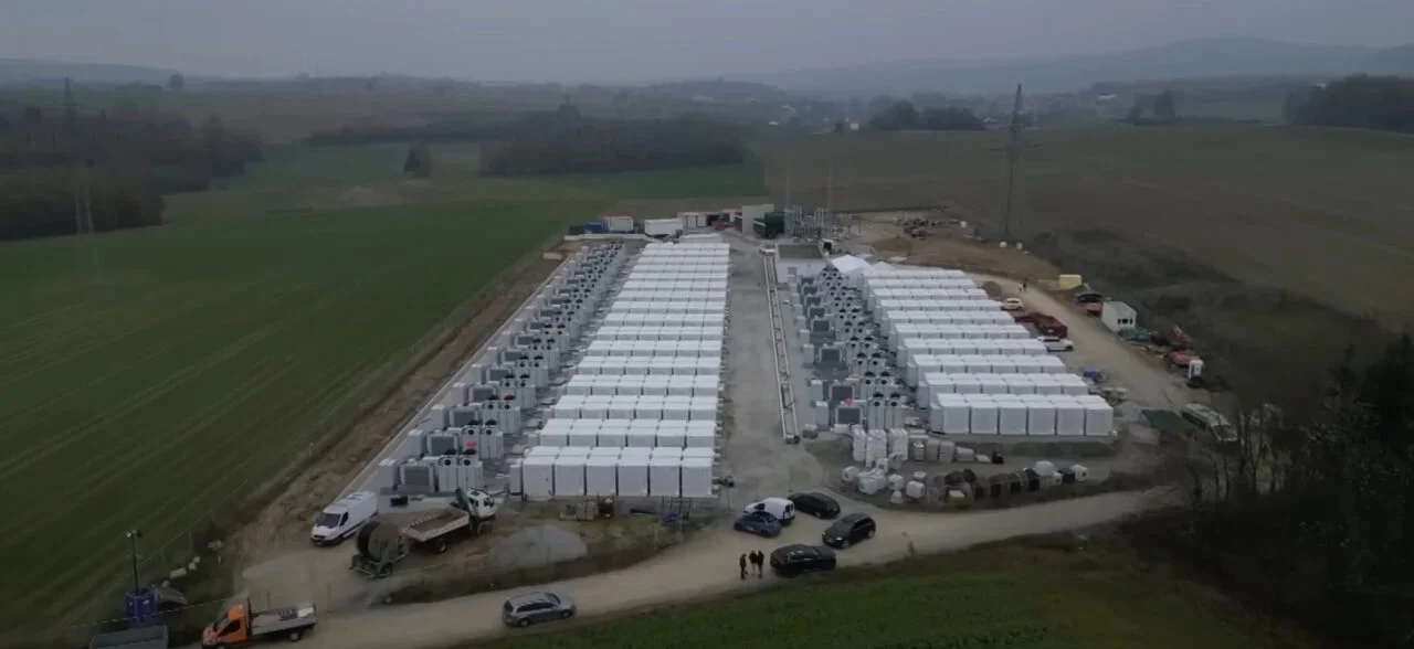Row of white utility-scale battery storage containers at a German renewable energy park