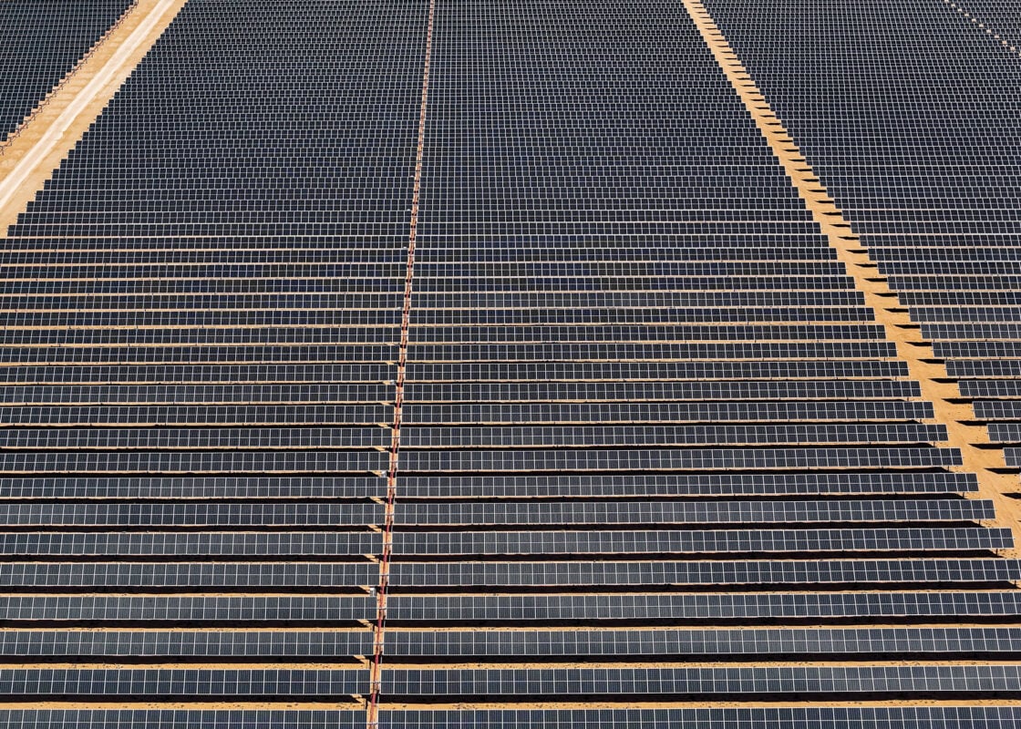 Aerial view of a massive utility-scale solar farm under construction with rows of trackers.