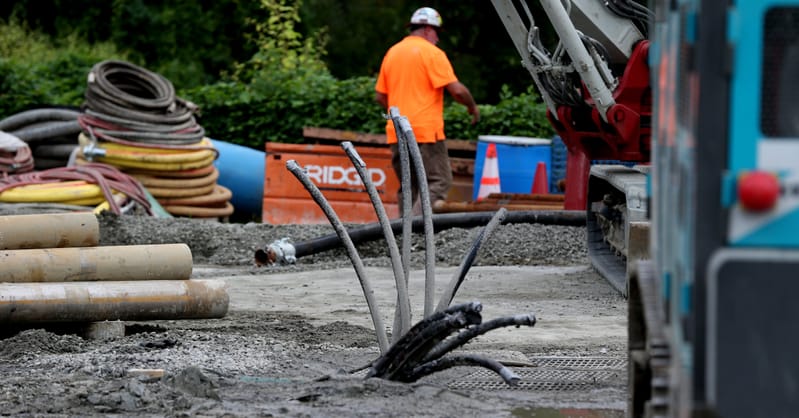 Workers installing underground thermal piping for a neighborhood geothermal network