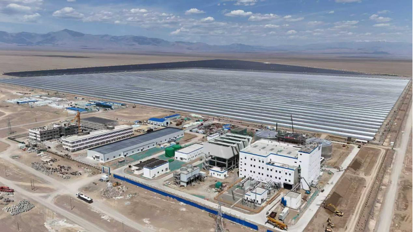 Large scale solar thermal tower surrounded by thousands of mirrors in a desert landscape.