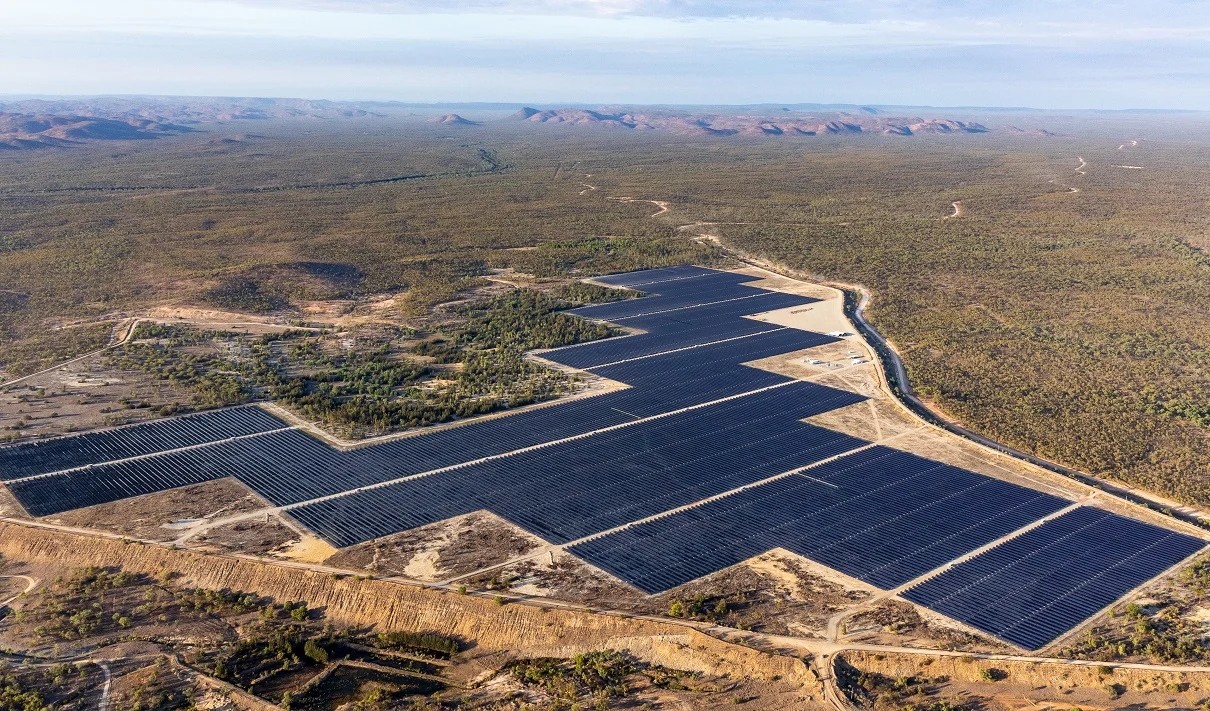 Large scale solar farm with industrial battery storage containers in a semi-arid landscape.