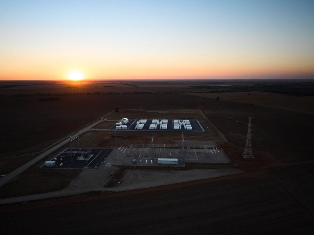 Row of large scale battery storage containers with grid-forming inverters in a field