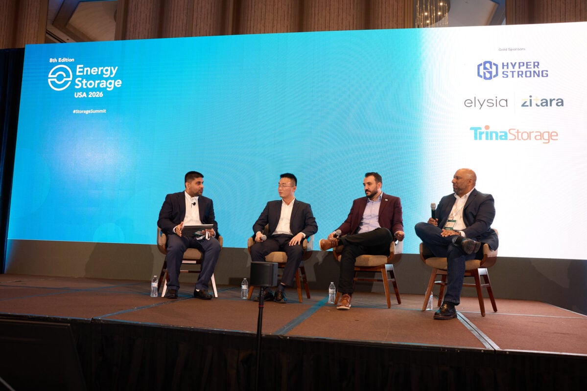 A rows of liquid-cooled battery storage containers sitting next to a high-density data center facility.