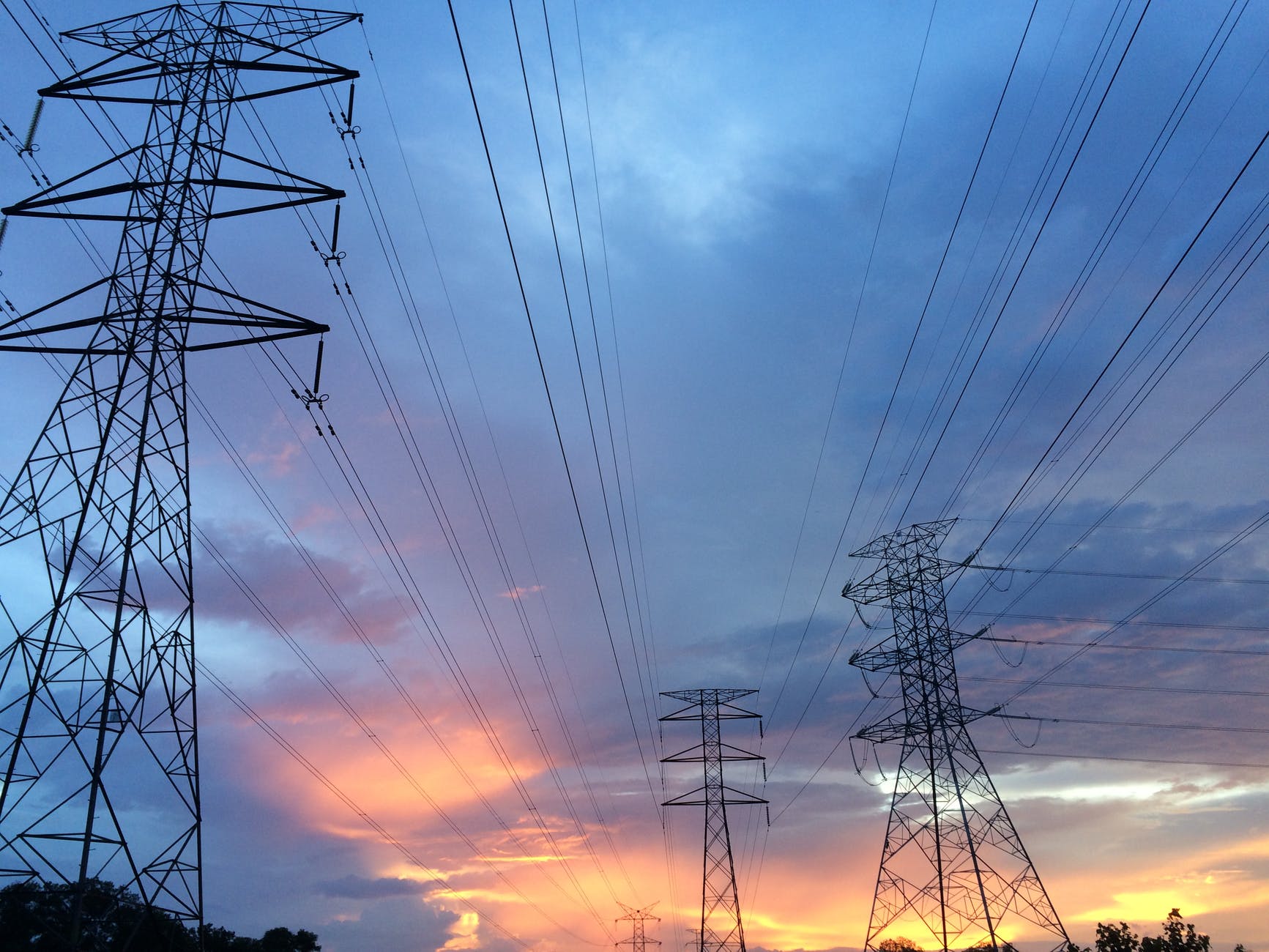 Large scale high-voltage transmission towers and power lines under a clear sky during construction.