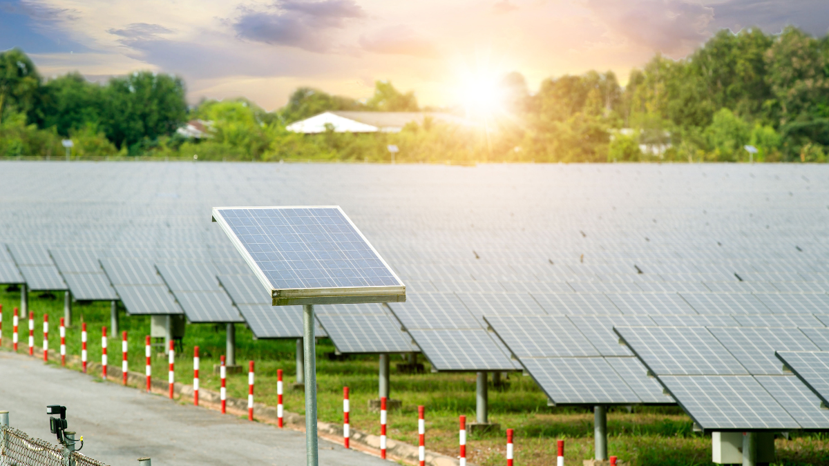Aerial view of a massive solar farm under a hazy, high-temperature summer sky.