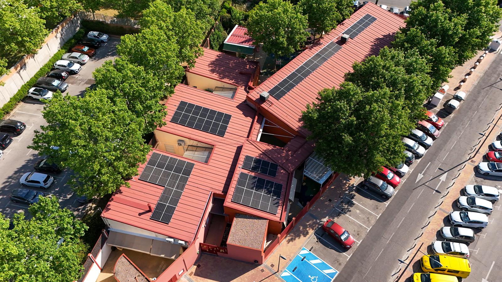 Solar panels installed on a flat roof of a public building in Spain with blue sky.