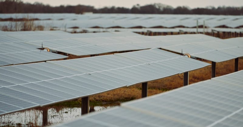 A modern residential home with rooftop solar panels and a battery storage system installed.