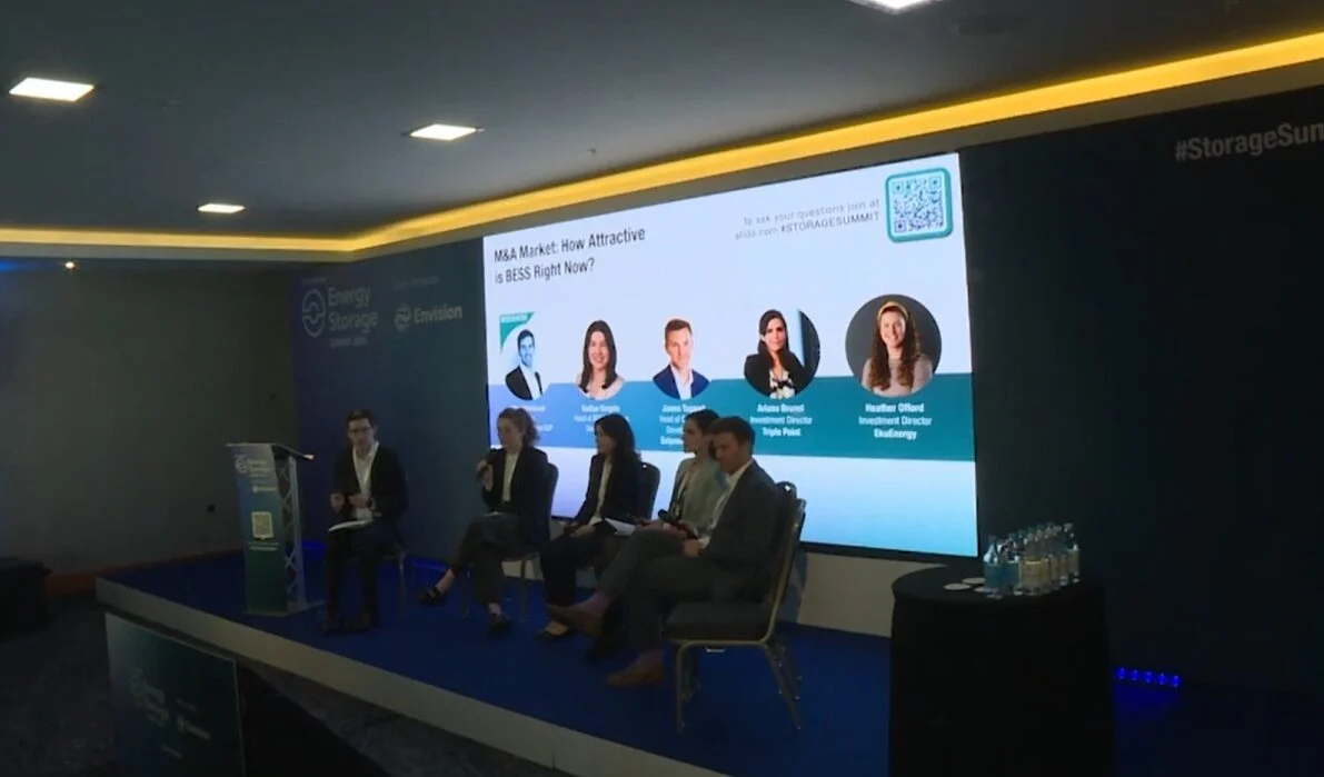 A row of industrial lithium-ion battery containers at a solar farm site.