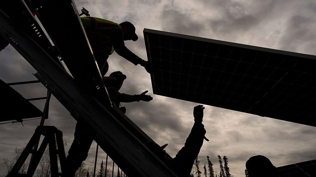 A professional solar installer inspecting rooftop photovoltaic panels under a bright European sky.