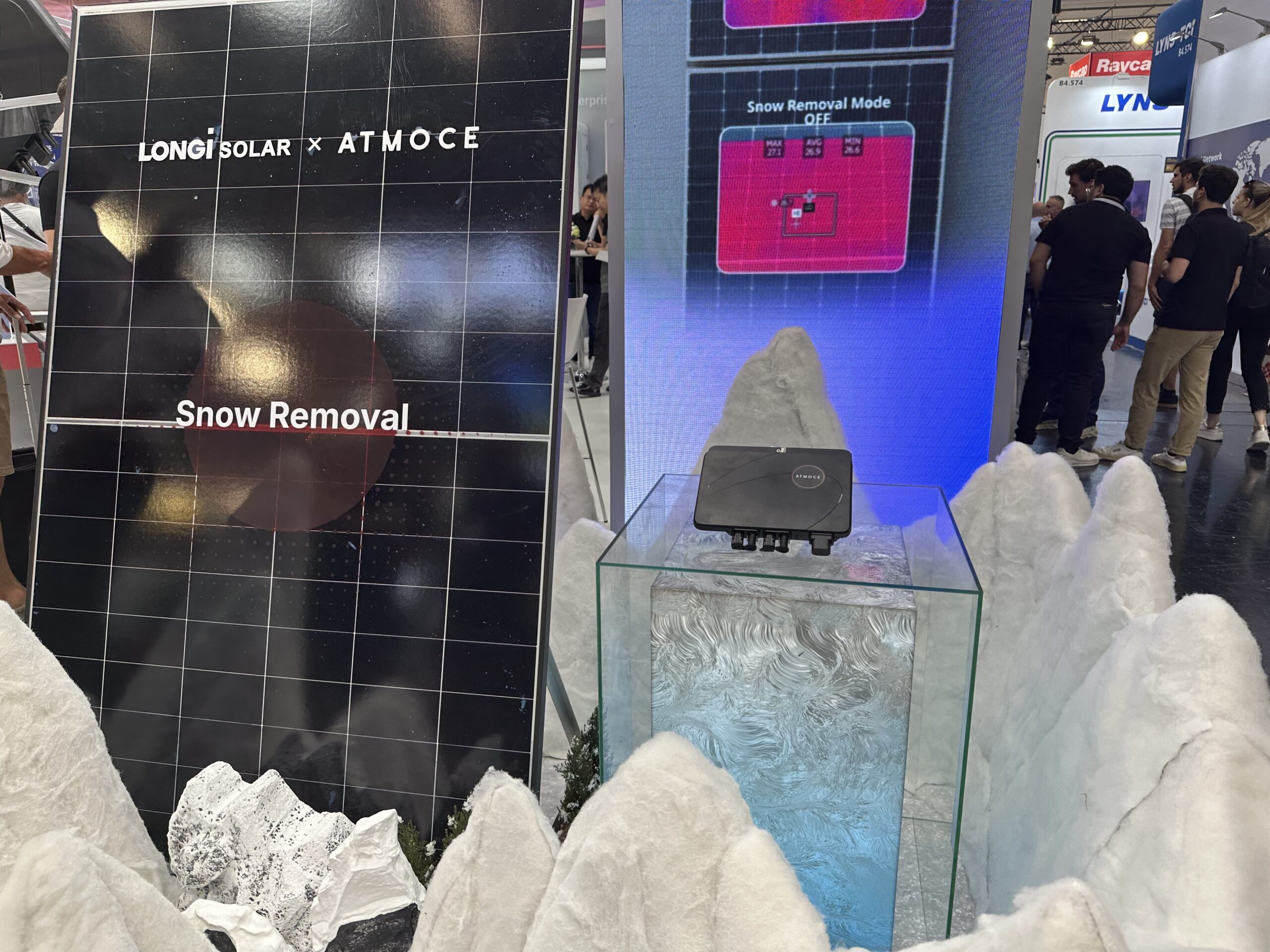 A solar panel partially covered in melting snow with a microinverter visible underneath.