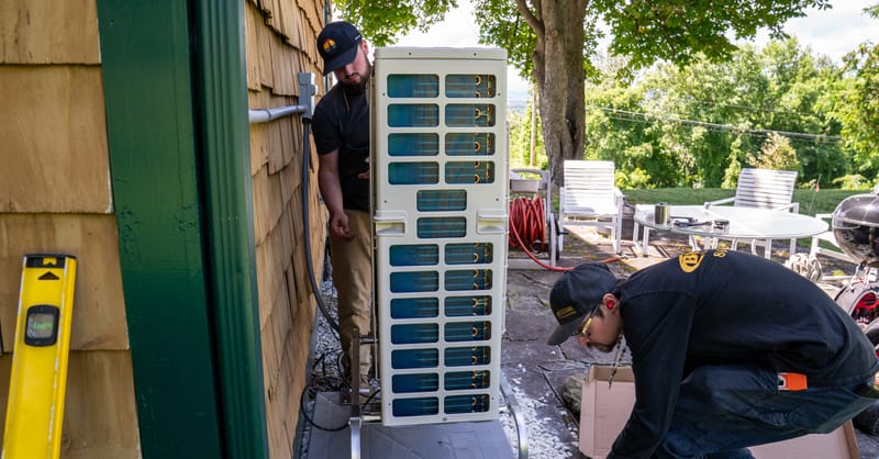 A technician installing a modern air-source heat pump in a residential garden setting