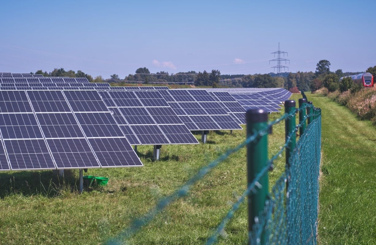Aerial view of a utility-scale solar farm in rural Poland under a dark, stormy sky.