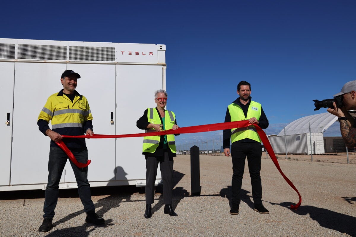 A large-scale utility battery storage facility with white containers and electrical infrastructure under a clear sky.