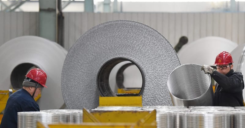 Workers inspecting solar panel aluminum frames in a modern, automated manufacturing facility in China.