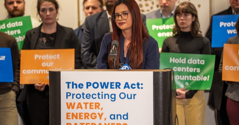A modern data center facility surrounded by a large-scale solar panel farm at sunset