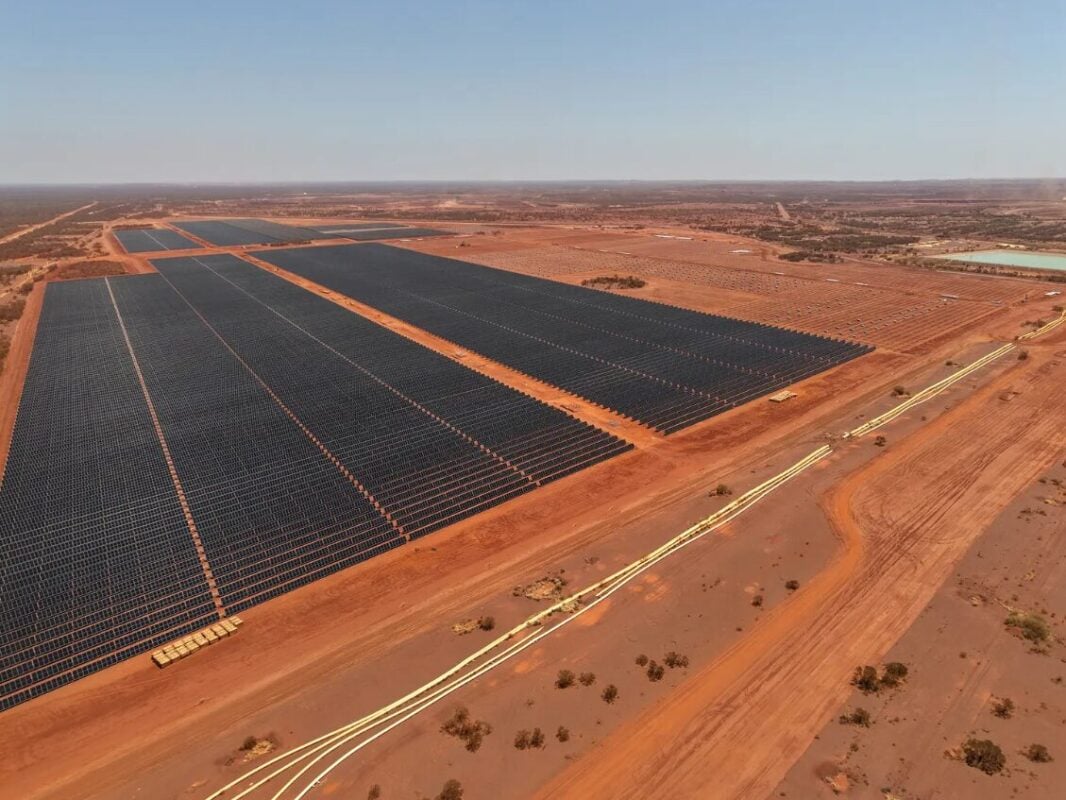 Aerial view of a large-scale solar farm with industrial battery storage containers in Western Australia