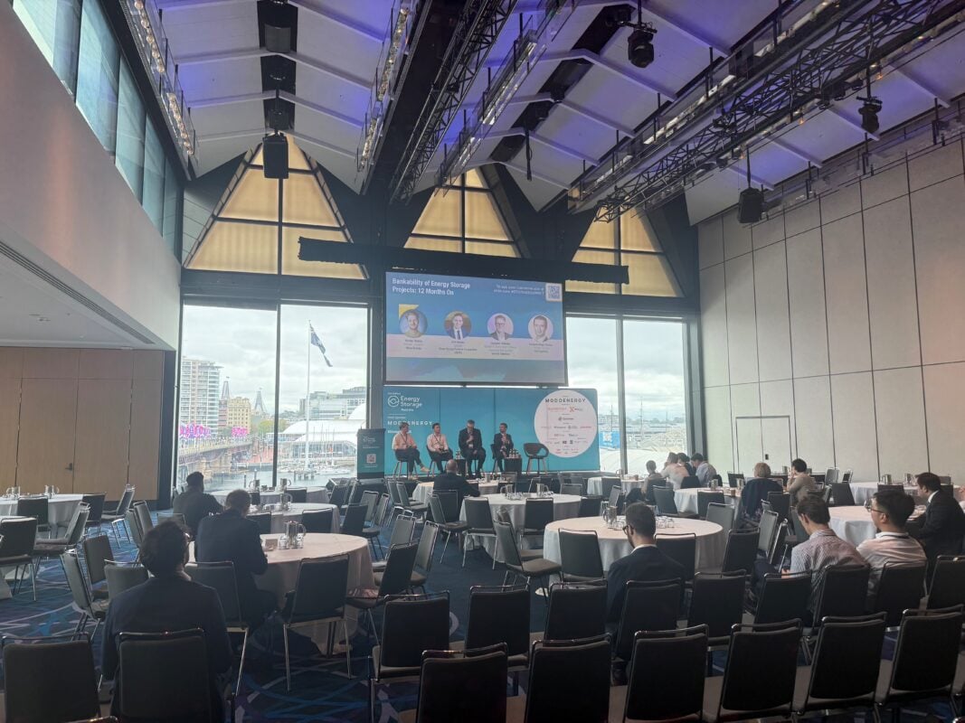 A technician inspecting a large-scale commercial battery storage installation in a European warehouse setting.