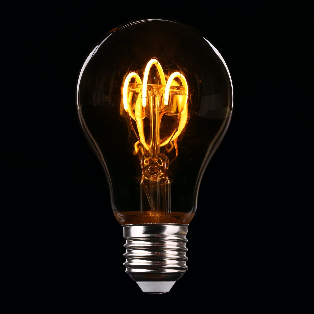 Close-up of a glowing light bulb filament representing electricity and energy investment trends.