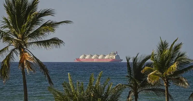 A massive cargo ship navigating the open ocean during sunset with industrial containers