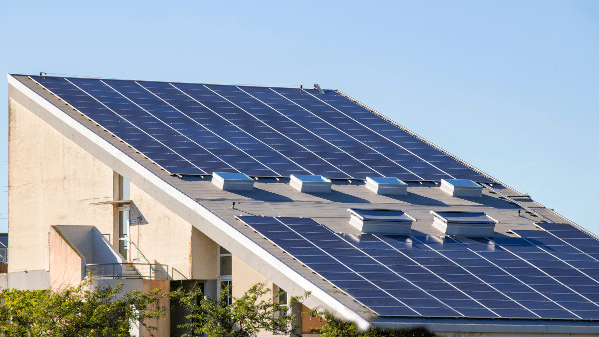 Solar panels on a rooftop being inspected by a professional with a clipboard, representing regulatory oversight.