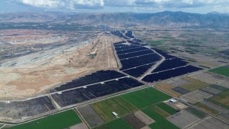 Aerial view of a massive utility-scale solar farm with rows of PV panels under a clear sky.