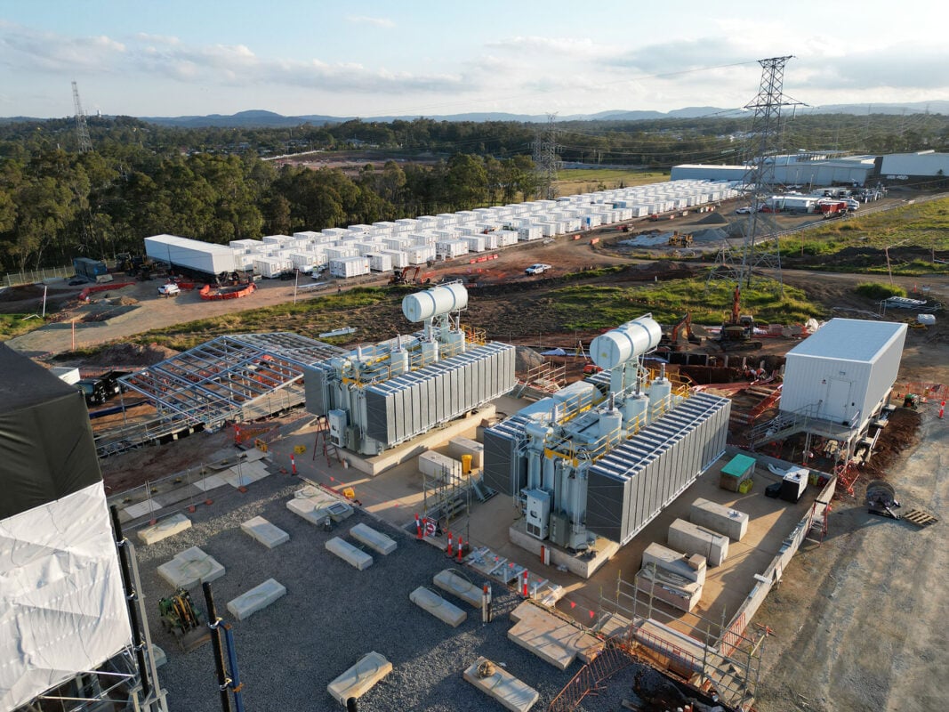 A massive utility-scale battery storage facility with lithium-ion containers under a bright sun.