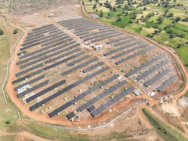 Aerial view of a massive utility-scale solar farm integrated with rows of white battery storage containers.